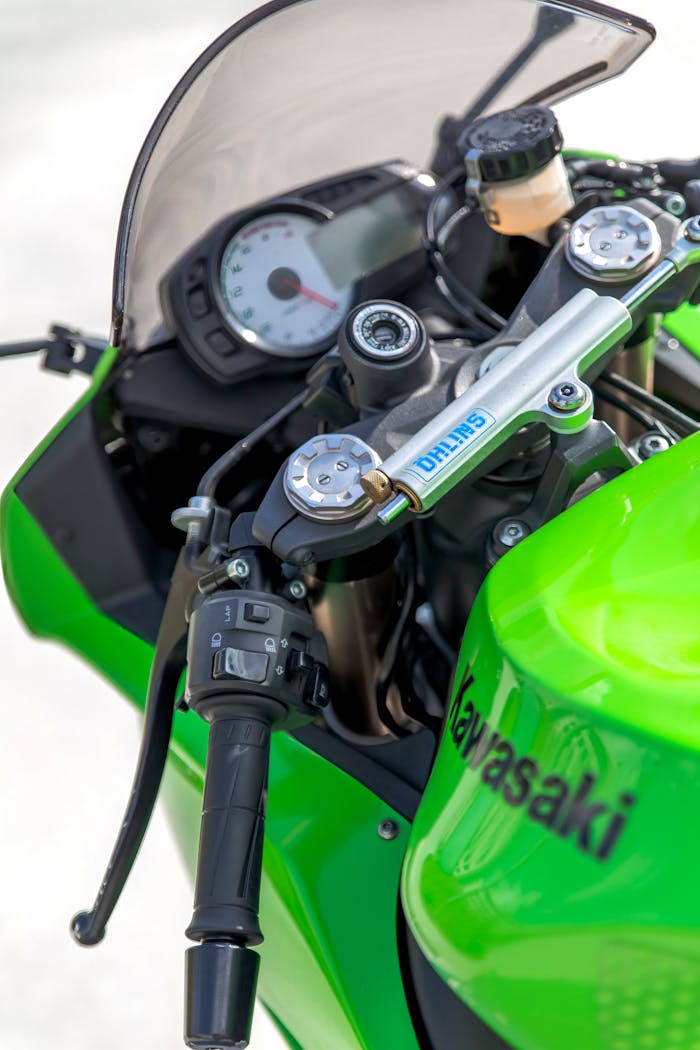 services-02 Detailed close-up view of a green Kawasaki motorcycle dashboard showcasing handlebars and instruments.